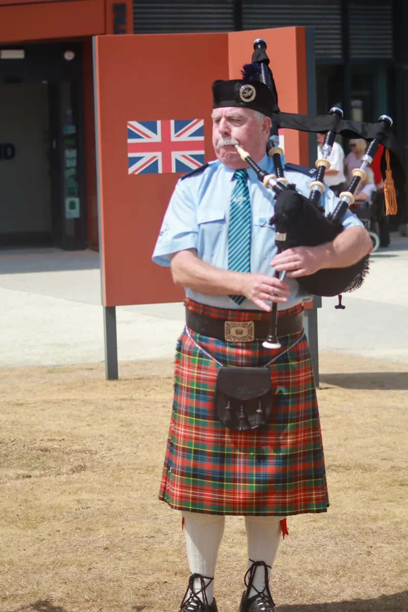 A Bomber County piper playing in front of a Union flag sign
